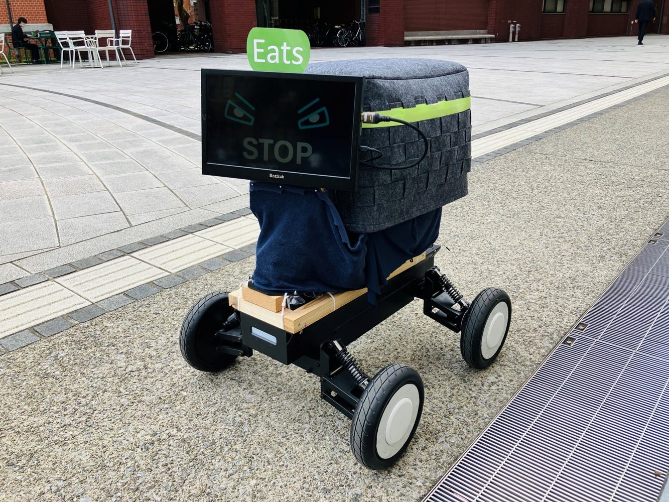Physical eHMI prototype with a display and movable head on a wheeled platform, outdoors.